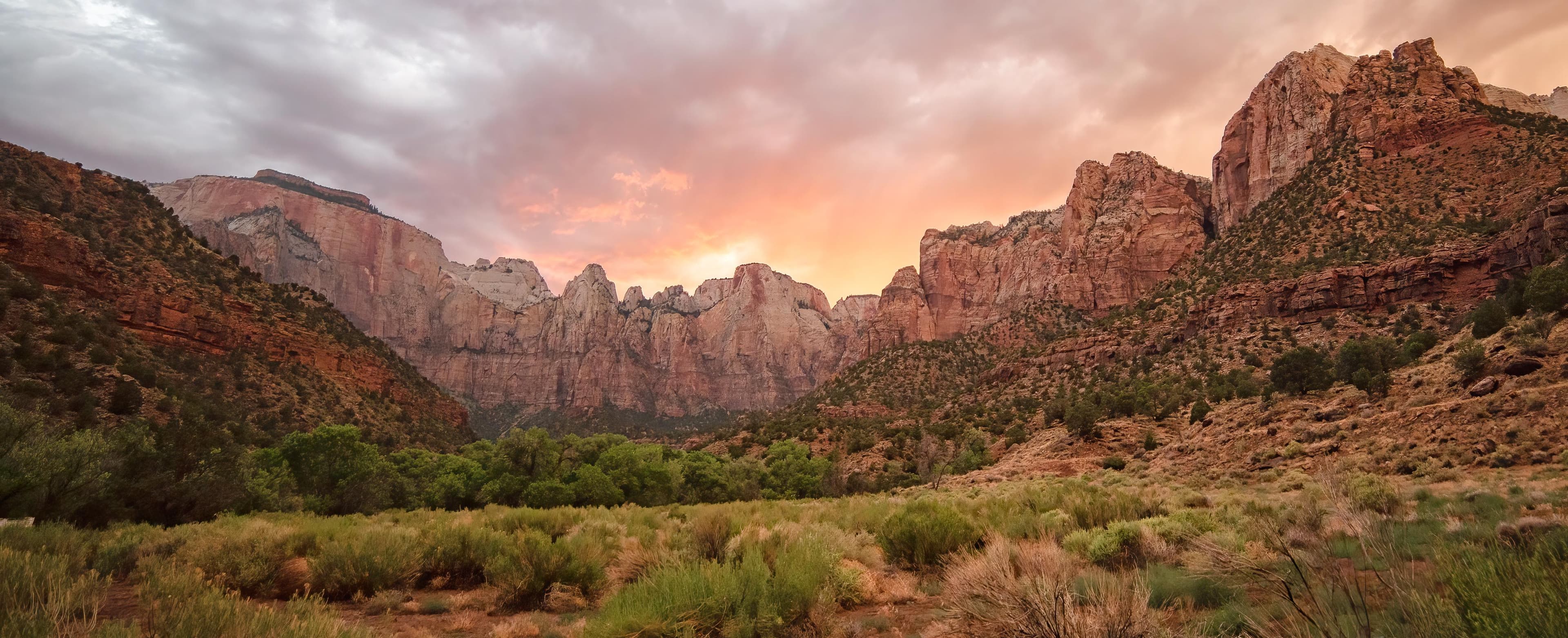 The sun sets behind large red and white towers of sandstone.